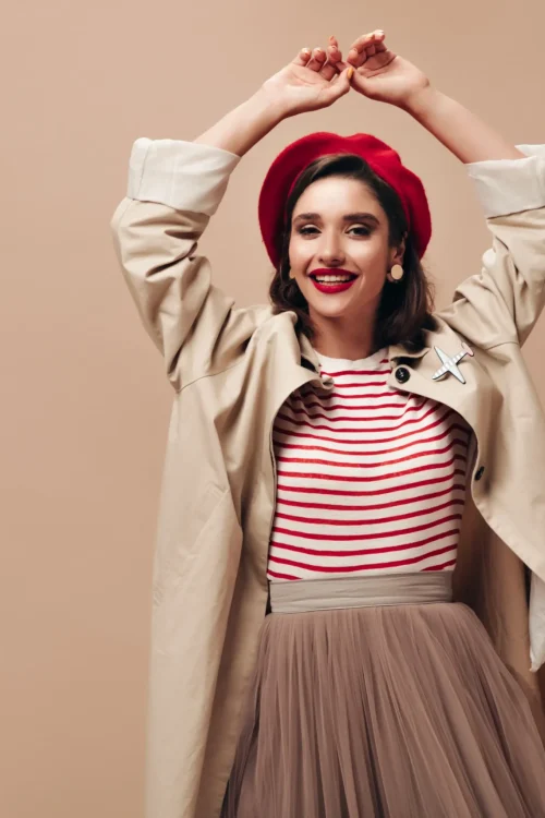 happy-woman-trench-stylish-beret-dancing-beige-background-charming-girl-striped-sweater-skirt-long-coat-smiles
